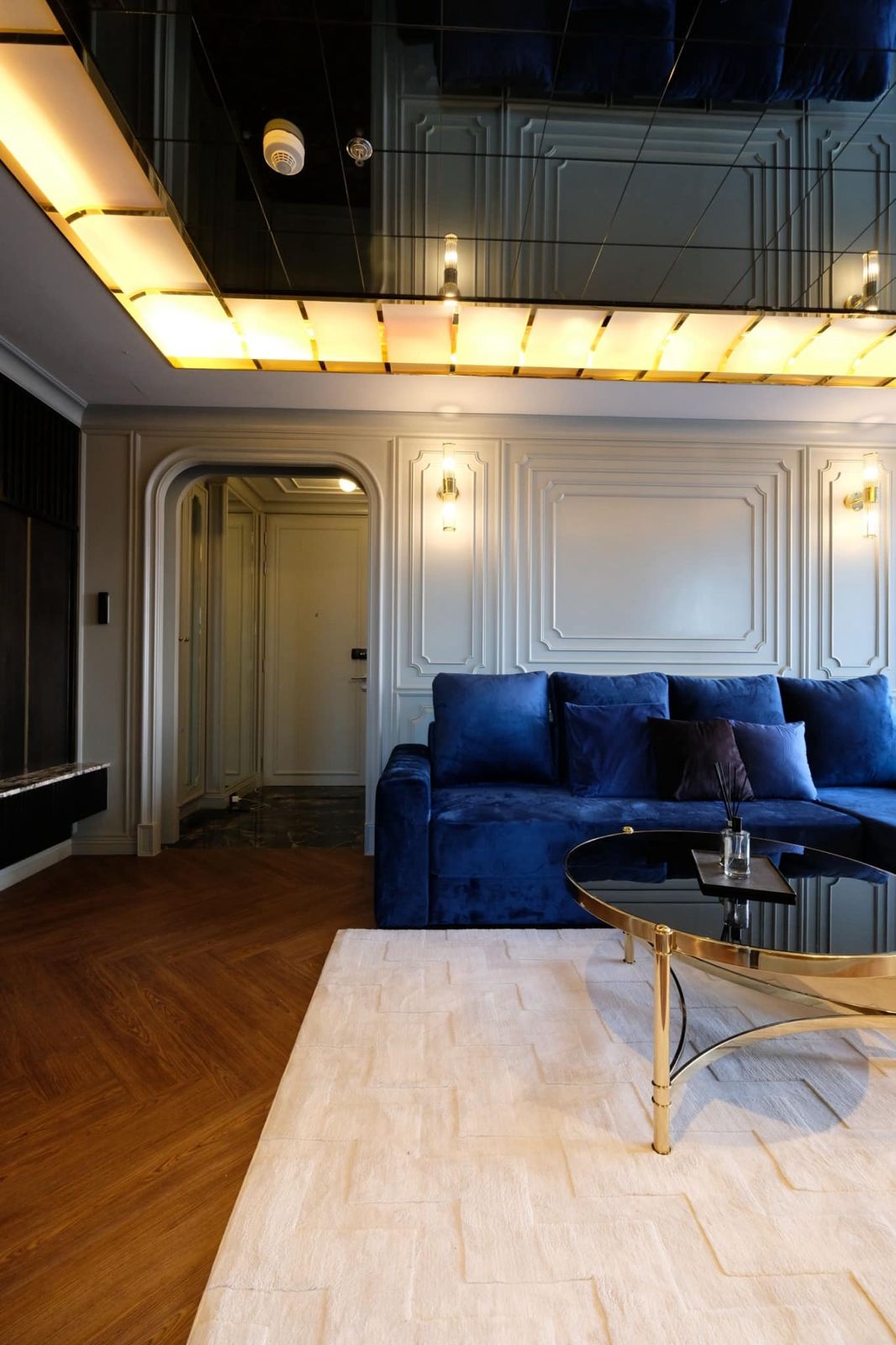 Living room with stylish lighting, detailed wall paneling, and a cozy sofa.
