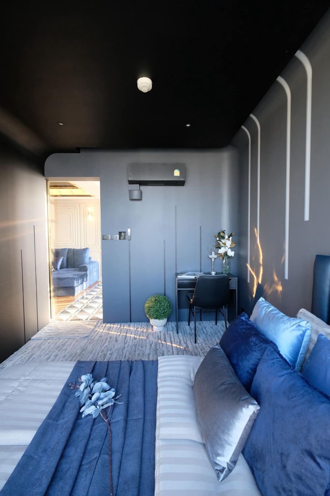 Sleek bedroom with dark tones, comfortable bed, and minimalist decor.