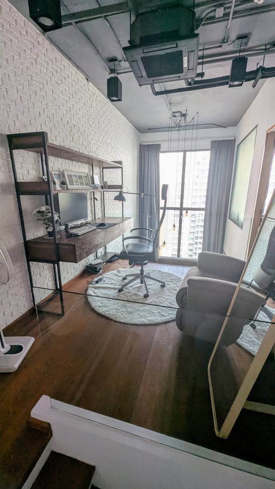 Spacious loft-style 1-bedroom duplex at Villa Asoke with high ceilings, floor-to-ceiling windows, modern furnishings, and city skyline views in Bangkok.